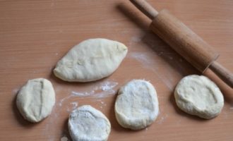 Rulla varje bit till en platt kaka eller forma dem med händerna. Tjockleken på kakorna är 5-7 mm. Placera fyllningen i mitten av kakorna, täta kanterna väl så att pajerna får en vacker form.