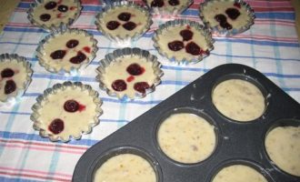 Smörj formarna med olja, så kan du baka cupcakes i både silikon- och metallformar. Därefter kan degen delas i två delar, i en av dessa tillsätt en sked apelsinskal. Dela degen i formarna, fyll dem till två tredjedelar. Lägg körsbär i degen utan skal och häll en liten mängd deg ovanpå bären.