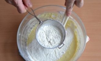 Använd en trä- eller silikonspatel, rör om innehållet i skålen och tillsätt siktat mjöl i två eller tre delar, knåda degen försiktigt.