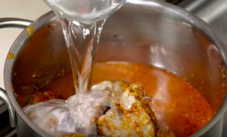 A continuació, aboqueu 2 gots d'aigua neta a la paella i deixeu coure la carn a foc lent durant 1 hora.