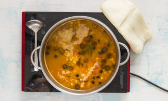 Đun sôi nước dùng và thêm tất cả các thành phần vào đó: toàn bộ danh sách các sản phẩm thịt, dưa chuột và nụ bạch hoa, ô liu cắt thành lát, hành tây chiên với bột mì và bột nhão, cũng như muối và gia vị. Đun sôi mọi thứ trong khoảng 10 phút, nếm thử và điều chỉnh lượng muối và gia vị nếu cần.