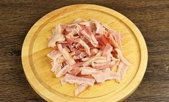 A baconos és tejszínes tészta carbonara elkészítéséhez először a szalonnát azonos méretű vékony csíkokra kell vágni.