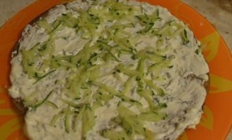 A következő tortaréteget kenjük meg szósszal, és tegyünk rá durva reszelőn reszelt friss uborkát. Befedjük tortával. Az összes réteget így rétegezzük, váltogatva a töltelékeket.
