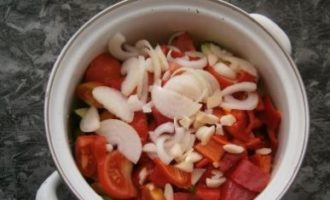 Snijd de teentjes knoflook in verschillende stukken en giet ze in de pan. Voeg ook de ui, in halve ringen gesneden, toe aan de groenten.