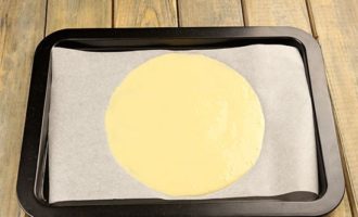 Egy tortaforma rajzolásához vegyünk sütőpapírt és valami nagy és kereket, például egy 20-22 cm átmérőjű fedőt, fordítsuk meg a papírt a mintával lefelé - ki fog látszani. Hogy ne ragadjon le a sütemény, ha nem olajozott a papírunk, kenjük meg egy kevés olajjal. A tésztát egy kanál segítségével nyújtsuk ki, 2-3 evőkanálnyit kikanalazunk belőle. Ne lépje túl a kört, egyenletesen ossza el a tésztát.