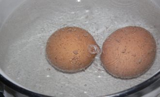 Hogyan készítsünk gránátalma karkötő salátát a klasszikus recept szerint? A tojásokat sós vízbe tesszük és 8 percig főzzük. A főtt tojásokat folyó hideg víz alatt lehűtjük.