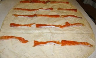 Repartiu el pa de pita sobre una superfície plana, unteu-lo bé amb formatge cremós, pareu atenció a les vores, això ajudarà a mantenir el rotlle. Poseu-hi trossos de salmó per sobre i espolseu-los amb llavors de sèsam, acabant el farcit amb fulles de julivert. Enrotllem el rotlle amb força, l'emboliquem amb paper film i el posem a la nevera uns 30-40 minuts com a mínim perquè el berenar es refredi i es remulli.