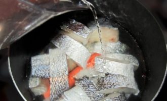 Häll 1,5 liter kallt vatten i fisken. Placera behållaren på medelhög värme. Tillsätt omedelbart skalade morötter och lök i buljongen.