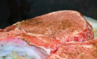 Puneți cotletele de porc pe patul de ceapă, presându-le strâns. Acoperiți tigaia cu un capac și gătiți carnea timp de 10 minute la foc foarte mic.