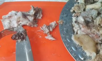 Bây giờ chúng ta lấy thịt ra và để nguội một chút, sau đó loại bỏ hết xương ở chân. Nhưng hành, tỏi và cà rốt không còn hữu ích với chúng ta nữa. Dùng dao băm nhuyễn thịt lợn có gân.