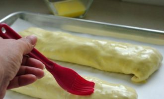 Lót giấy vào khay nướng và bôi một ít dầu thực vật lên khay nướng. Đặt các cuộn bánh lên khay nướng, mặt đường may hướng xuống dưới. Trộn một lòng đỏ với một thìa cà phê nước và phết hỗn hợp lên các cuộn bánh.