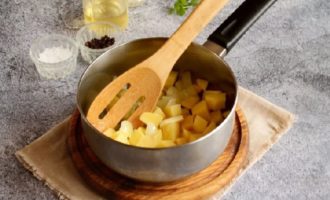 Poseu una cassola de fons gruixut al foc, afegiu-hi oli vegetal o d'oliva i comenceu a escalfar. En aquest moment, talleu la ceba a trossos més petits i talleu els tubercles de patata a daus o daus. Primer, poseu la ceba a la cassola i, al cap d'un minut, les patates. A continuació, afegiu-hi els alls, prèviament triturats amb una premsa d'alls. Barregeu els ingredients i fregiu durant un minut aproximadament a foc lent.