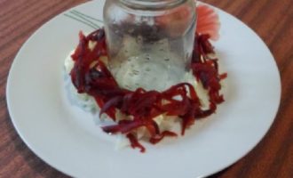 Agafeu un plat pla i ample i poseu-hi un pot o got de mig litre al centre. Col·loqueu una capa de patates al voltant del pot, salpebreu lleugerament i cobreu-ho amb maionesa. Col·loqueu la meitat de la remolatxa, la maionesa per sobre, després les pastanagues i els ous, arrebossem amb maionesa.