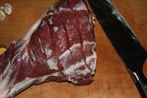 Để nướng thịt cừu ngon trong lò, hãy rửa sạch miếng thịt dưới vòi nước chảy và lau khô bằng khăn. Sau đó thực hiện nhiều vết cắt sâu vào thịt. Bóc vỏ tỏi và cắt thành từng miếng dài. Đặt tỏi vào các vết cắt trên thịt.
