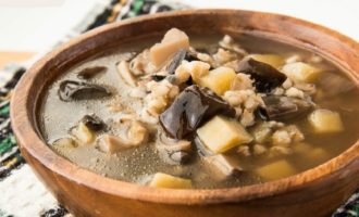 Afegiu patates, all, xampinyons, ceba i pastanagues a la paella d'ordi, afegiu sal i espècies. Coure a foc lent fins que les patates estiguin a punt durant uns 20 minuts.A continuació, afegiu-hi julivert picat finament, deixeu-ho bullir i retireu la cassola del foc. Serviu la sopa amb crostons i crema agra.