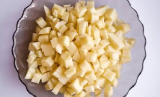 Ara cal preparar les verdures. Peleu els tubercles de patata i esbandiu les patates amb aigua corrent per eliminar tota la brutícia. Talleu les patates netes a daus petits i afegiu-les a la paella a la carn de vedella, que ja ha estat bullida durant 1,5 hores.
