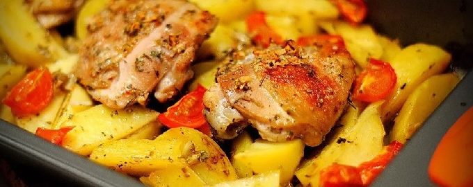 Kyckling med potatis i ugnen på en plåt