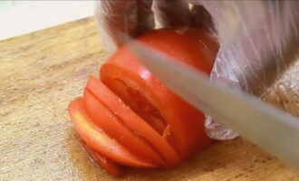 Tvätta tomaten, torka den och skär den i halvcirklar.