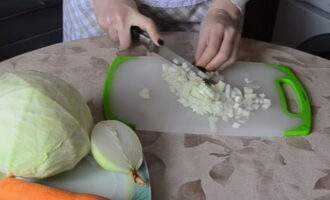 La col estofada en una paella es prepara de manera ràpida i senzilla. Al principi, cal preparar les cebes: pelar-les i després tallar-les.