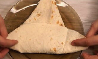 Tiklupin ang mga gilid ng tinapay na pita patungo sa gitna, pindutin nang mabuti upang bumuo ng isang tatsulok.