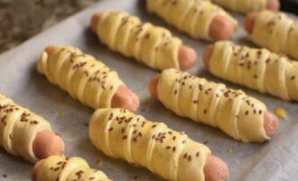 Folosind o perie de silicon, ungeti fiecare bucata cu galbenus si presarati seminte de in deasupra. Puneți viitoarele produse de copt timp de 20-25 de minute la cuptor, preîncălzit la 200 de grade.