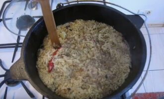 Als er nog water over is, gebruik dan een houten lepel om gaten rond de cirkel van de ketel te maken. Kook de pilaf tot het water volledig is verdampt.