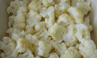 Grasa ang baking dish na may mantikilya, hindi nakakalimutan ang mga gilid. Inilalagay namin ang mga pinatuyong inflorescences ng cauliflower dito - sinusubukan naming ipamahagi ang mga ito nang pantay-pantay sa buong perimeter.