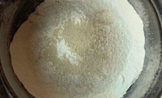 Upang maghanda ng pizza dough na may kefir, salain ang harina sa isang malalim na mangkok. Paghaluin ito sa natitirang mga tuyong produkto: soda, asin at asukal.