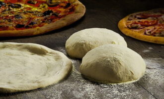 Iwanan ang nagresultang bukol ng kuwarta sa loob ng 10-15 minuto, at pagkatapos ay iwisik ng harina at gumulong sa isang manipis na layer. Kefir pizza dough na walang lebadura ay handa na!