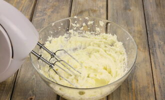 Låt oss gå vidare till att förbereda det krämiga lagret. Blanda rumstempererad färskost i en skål med socker och vispa ihop allt med en mixer på hög hastighet tills sockerkornen löst sig.