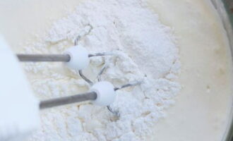 Cerneți zahărul pudră în smântâna groasă și adăugați extract de vanilie. Amestecați ușor cu un mixer.