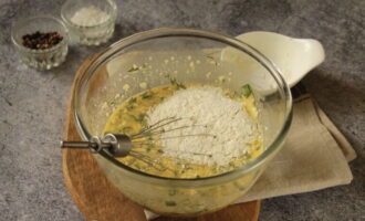 Voeg vervolgens gehakte kruiden, zout, zwarte peper toe en zeef de bloem. Klop de inhoud totdat de klont verdwijnt.