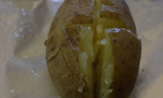 După gătire, scurgeți apa și lăsați cartofii să se răcească la o temperatură confortabilă. Pentru fiecare cartof pregatim cate o bucata de folie dupa marime. Stropiți puțin ulei vegetal pe fiecare bucată de folie. Ungem și suprafața cartofilor cu ulei. Facem o tăietură în formă de cruce pe fiecare legumă. Puneți o bucată mică de unt în tăietură.