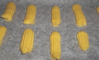 Bedek de bakplaat met geolied perkament. We planten er langwerpige eclairs van de gewenste lengte op. We laten voldoende ruimte tussen de stukken - het deeg neemt tijdens het bakken aanzienlijk in volume toe.