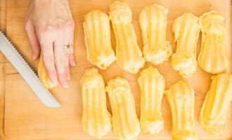 Verwarm de oven voor op 180 graden.Plaats de bakplaat met de beklede eclairs op het middelste niveau en bak ze gedurende dertig tot vijfendertig minuten. Tijdens het proces openen we de deur niet, maar beoordelen we de mate van gereedheid van de taarten visueel door het glas. Kant-en-klare eclairs moeten goed rijzen en aan alle kanten bruin worden. Wanneer de baktijd van de eclairs is verstreken, zet u de oven uit en laat u de producten nog vijf minuten staan. Vervolgens halen we de gebakken producten eruit en brengen ze van de bakplaat naar een bord om af te koelen. Snij de afgekoelde eclairs in de lengte door en vul de binnenruimte met gekookte gecondenseerde melk.