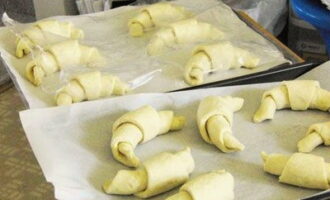 Col·loquem paper sulfuritzat en una safata de forn, sobre la qual col·loquem croissants fets amb pasta de full. Tapeu-los amb paper film i deixeu-los reposar en un lloc càlid durant 30-40 minuts.