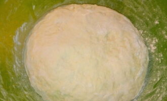 Ibuhos ang natitirang harina sa masa sa mga bahagi, pagkatapos na salain ito. Masahin ang kuwarta gamit ang iyong mga kamay. Kapag nabuo na ang masa, magdagdag ng walang amoy na langis ng gulay at ipagpatuloy ang pagmamasa. Binubuo namin ang kuwarta sa isang makinis na bola, ilagay ito sa isang mangkok, takpan ng isang tuwalya o takpan ng cling film at ilagay sa isang mainit na lugar upang patunayan sa loob ng apatnapu hanggang limampung minuto.