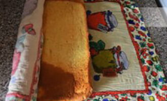 Plaats het afgewerkte biscuitgebak terwijl het nog heet is op een vochtige handdoek en wikkel het in een rol. Dit is een heel belangrijk punt.