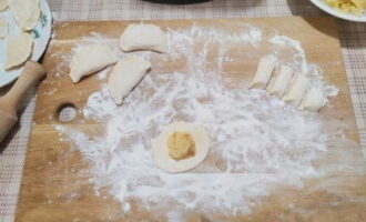 Rol het deeg uit tot een worst en snijd het in kleine stukjes. Rol elk deel uit tot een platte cake, doe een beetje vulling in het midden en wikkel de dumpling. Doe dit met al het deeg en de vulling.Plaats de afgewerkte dumplings voorzichtig op een bord of snijplank en bestrooi ze met bloem zodat ze niet aan elkaar plakken. Rol het deeg uit tot een worst en snijd het in kleine stukjes. Rol elk deel uit tot een platte cake, doe een beetje vulling in het midden en wikkel de dumpling. Doe dit met al het deeg en de vulling. Plaats de afgewerkte dumplings voorzichtig op een bord of snijplank en bestrooi ze met bloem zodat ze niet aan elkaar plakken.