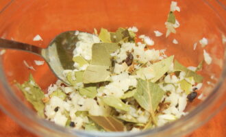 Habang lumalamig ang mantika, maghanda ng pinaghalong pampalasa para sa pag-atsara. Balatan ang bawang at i-chop ito ng pino gamit ang kutsilyo. Durugin ang bay leaf gamit ang iyong mga kamay nang pino hangga't maaari. Durugin ang allspice peas gamit ang kutsilyo hanggang sa gumuho. Paghaluin ang lahat sa isang maliit na mangkok.