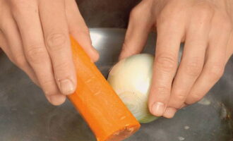 Pentru a găti supa de varză din varză murată, turnați 2 litri de apă rece într-o tigaie și puneți carnea în ea. Se aduce la fierbere la foc mare. În acest moment, curățați un morcov și ceapa. După ce fierbe bulionul, reduceți focul. Îndepărtați spuma rezultată și adăugați legume. Gatiti timp de o ora si jumatate.