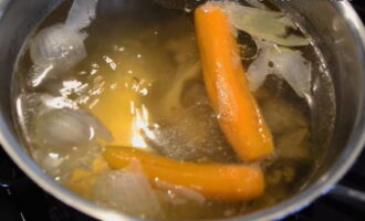 Snijd de ui en de wortels willekeurig in grote stukken, voeg ze toe aan de bouillon en kook verder. Zeef de afgewerkte bouillon, gooi de uien en wortels weg, verwijder het vlees van de botten en snijd het in kleine stukjes. Doe de in blokjes gesneden aardappelen in de gezeefde bouillon en kook op laag vuur tot ze gaar zijn. 