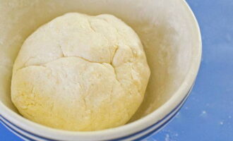 Comenceu a barrejar tots els ingredients amb una cullera. Quan sentiu que es fa massa difícil pastar-los, transferiu la barreja a una superfície enfarinada i continueu pastant la massa amb les mans. Un cop estigui homogeni i no s'enganxi a les mans, formeu-hi una bola i poseu-la a la nevera durant una hora. Això és necessari perquè la farina absorbeixi més humitat, de manera que la massa es tornarà flexible i elàstica i no s'esmicolarà. Quan arribi el moment, retireu-lo de la nevera i deixeu-lo a temperatura ambient uns 10 minuts perquè s'escalfi.