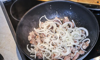 Schil de ui en snij in halve ringen. Voeg de ui toe aan het vlees in de pan, voeg zout toe en bak verder tot de ui zacht is.