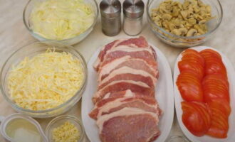 Paano magluto ng French pork meat na may keso at mushroom sa oven? Ihanda ang lahat ng sangkap. Gupitin ang karne sa manipis na piraso na 1.5 cm ang kapal, talunin ito ng mahina.Mas mainam na i-cut ang karne sa buong butil - makakakuha ka ng mga 8 piraso. Gupitin ang sibuyas sa kalahating singsing at ang mga kamatis sa mga singsing. Grate ang keso at makinis na tumaga ang bawang.