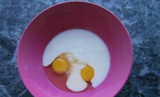 Cum se prepară un aluat delicios de chefir pentru o plăcintă? Spargeți două ouă de pui într-un castron adânc, care este convenabil pentru amestecare. Turnăm și chefir aici.