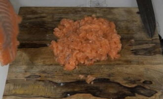 Hoe maak je heerlijke en sappige roze zalmkoteletten klaar? Dit recept gaat uit van het gebruik van filets, dus het proces van het snijden van de vis is niet inbegrepen in het kookproces. Bovendien kunt u met het gebruik van filet uw tijd aanzienlijk besparen. We zullen gehakte koteletten maken. Daarom is het niet nodig om vis te malen met een vleesmolen of blender. Snijd de filet met een gewoon scherp keukenmes in kleine stukjes. De blokjes moeten elk ongeveer 5 millimeter groot zijn. Uiteraard hoeft u deze afmetingen niet helemaal exact aan te houden. U hoeft zich alleen maar aan deze parameter te houden. 