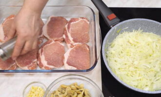 Simulan ang pagprito ng mga sibuyas. Ibuhos ang langis ng gulay sa isang kawali at iprito ang sibuyas. Sa oras na ito, ilagay ang karne sa isang baking sheet o sa isang amag. Paminta at asin ang karne sa panlasa.