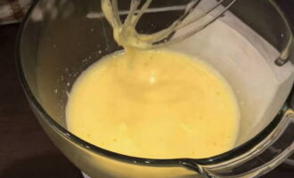 I en separat skål, vispa äggen med en mixer tills de är fluffiga. Tillsätt socker i blandningen och vispa igen tills blandningen blir vit och ökar i volym.