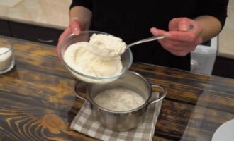 A continuació, sense tamisar la farina, afegiu-hi 120 grams de la quantitat total i barregeu la massa. La consistència de la massa ha de semblar una crema agra rica. Tapeu la paella amb una tapa i deixeu-ho en un lloc càlid fins que la massa augmenti de volum.